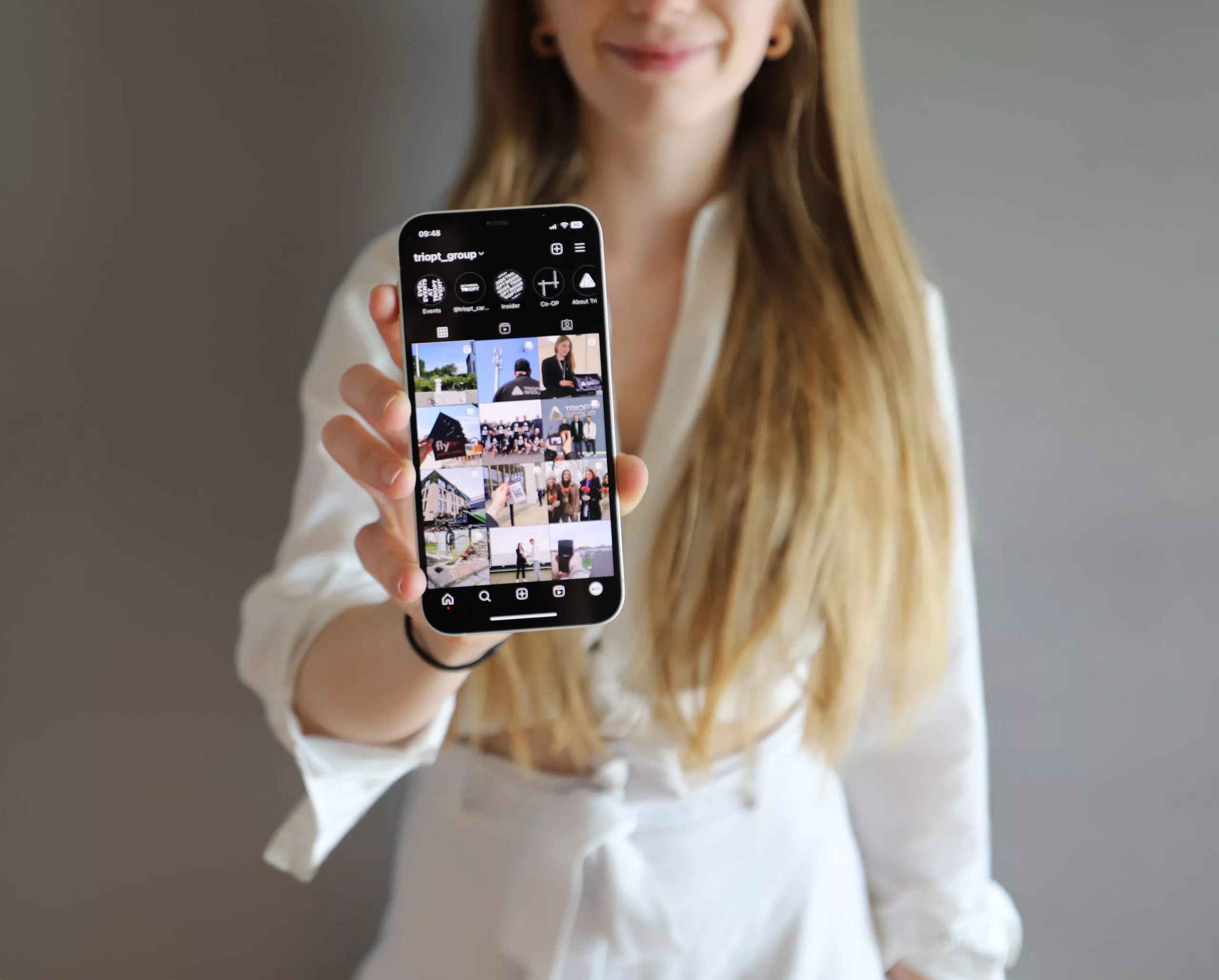 Mitarbeiterin der Triopt Group hält die Unternehmensseite von Instagram in die Kamera